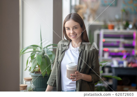 Smiling beautiful woman having a coffee at the workplace Smiling beautiful woman having a coffee at the workplace 62072603