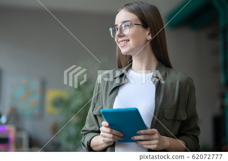 Happy girl in glasses with a tablet in her hands. Happy girl in glasses with a tablet in her hands. 62072777