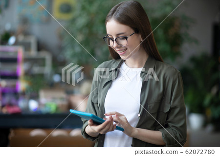 Young girl in glasses with a tablet in her hands. 62072780