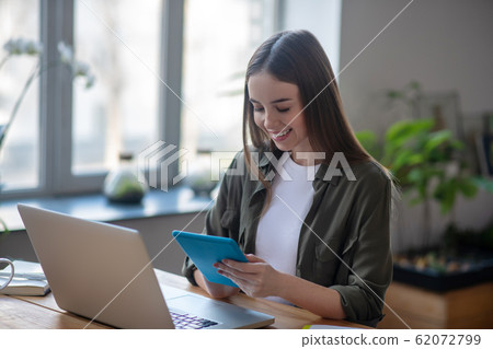 Nice joyful girl with a tablet in her hands. 62072799