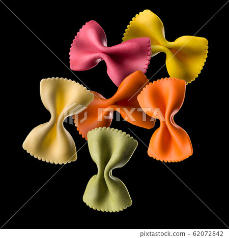 Flying colourful farfalle pasta isolated on black background Flying colourful farfalle pasta isolated on black background 62072842