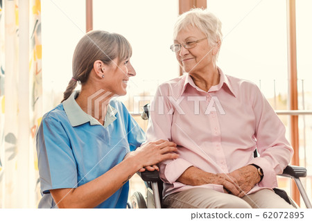 Caregiver with senior woman in pension home 62072895