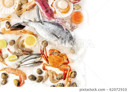 Fish and seafood variety, shot from the top on a white background with copy space. Fish, shrimps, crab, squid, clams, scallops, a design template with a place for text 62072910