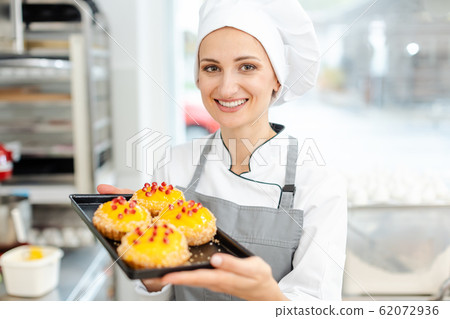 Pastry chef putting cranberries on top of little tartelettes 62072936