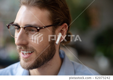 Happy face of man in glasses and in one wireless earpiece. 62073242
