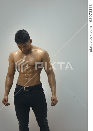 Tired Muscular Asian Man Indoors in Studio 62073358