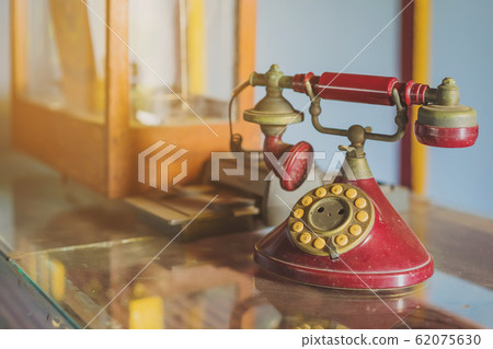 A red telehones with rotary dial with dust and scratches and credit card machine in ancient times placed on a glass showcase in an old gold shop in Asia. 62075630