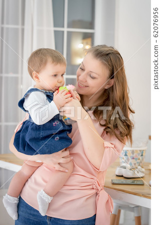 Mother holds 1 year old daughter and gives her a Mother holds 1 year old daughter and gives her a 62076956