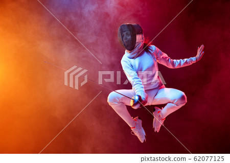 Teen girl in fencing costume with sword in hand isolated on black background Teen girl in fencing costume with sword in hand isolated on black background 62077125