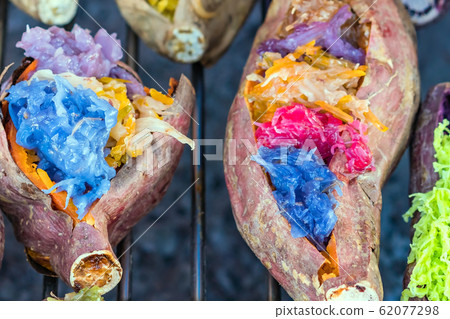 Colorful of many Thai traditional desserts stuffed in grilled yams on stove for sale on street food. Colorful of many Thai traditional desserts stuffed in grilled yams on stove for sale on street food. 62077298