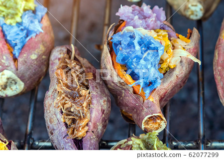 Colorful of many Thai traditional desserts stuffed in grilled yams on stove for sale on street food. Colorful of many Thai traditional desserts stuffed in grilled yams on stove for sale on street food. 62077299