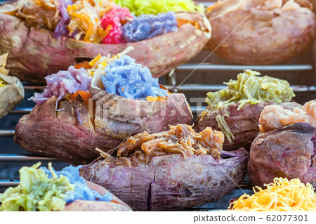 Colorful of many Thai traditional desserts stuffed in grilled yams on stove for sale on street food. Colorful of many Thai traditional desserts stuffed in grilled yams on stove for sale on street food. 62077301
