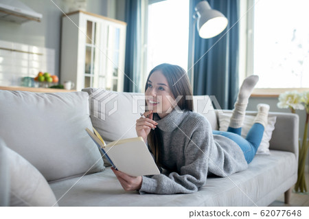 Young girl in a grey sweater thinking over a new idea Young girl in a grey sweater thinking over a new idea 62077648