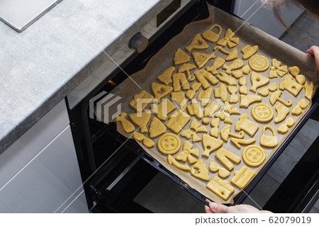 Removing cookies from the oven. Cooking cookies at 62079019