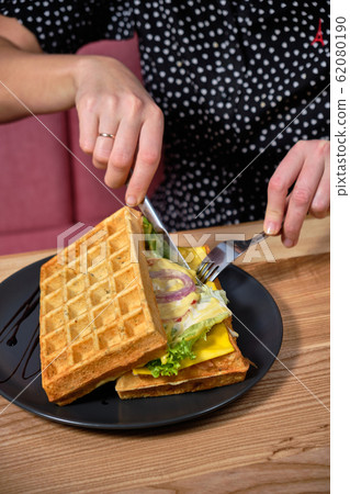 Woman slices a wafer covered in cheese with Woman slices a wafer covered in cheese with 62080190