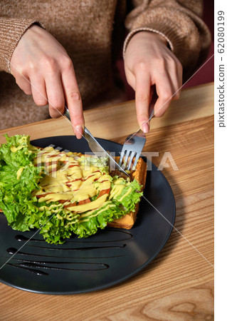 Woman slices a wafer covered in cheese with 62080199