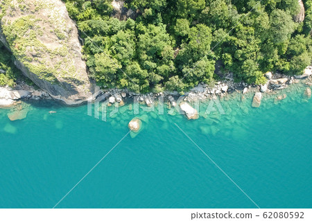 top view aerial shot with drone of green rocky forest and blue water top view aerial shot with drone of green rocky forest and blue water 62080592