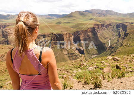 female hiking tourist at the edge of a cliff overlooking the canyons female hiking tourist at the edge of a cliff overlooking the canyons 62080595