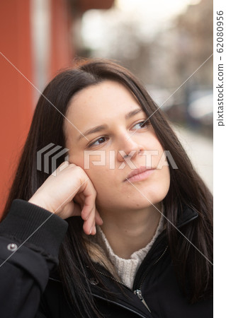 Close-up portrait of a pensive and lonely young brunette woman with a dreamy gaze Close-up portrait of a pensive and lonely young brunette woman with a dreamy gaze 62080956