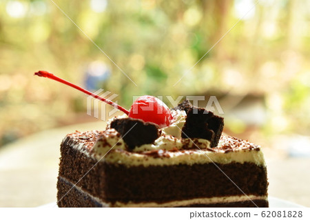 black fotest cake with cream topping cherry on plate 62081828