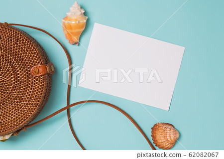 Seashells and ratan bag on blue background, top view. Seashells and ratan bag on blue background, top view. 62082067