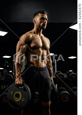 Pumped male bodybuilder holding weights. 62082870