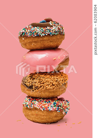 Donuts one on each other with icing and chocolate on pink background. Sweet donuts 62083904