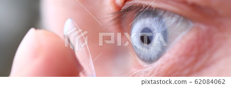 Man putting on soft contact lens Man putting on soft contact lens 62084062