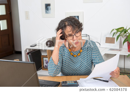 mature woman paying bills with laptop at home mature woman paying bills with laptop at home 62084378