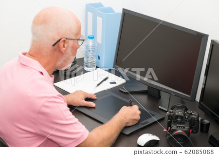 mature man working with  graphics tablet in his 62085088
