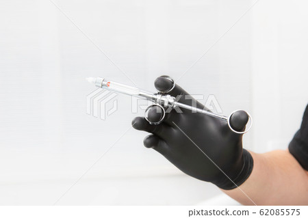 Dentist's hand in a black glove holding a dental Dentist's hand in a black glove holding a dental 62085575