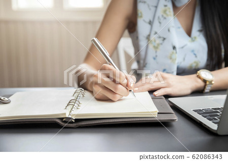 Close up of Woman's hands and writing on notebook Close up of Woman's hands and writing on notebook 62086343