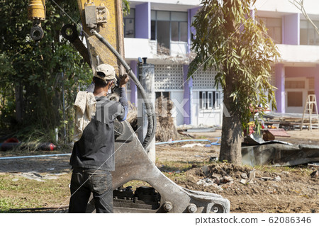 The mechanic is repairing the arm of the drilling excavator. 62086346