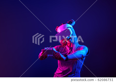 Woman is using virtual reality headset. Neon light studio portrait. 62086731