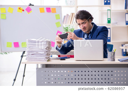 Young male employee unhappy with excessive work Young male employee unhappy with excessive work 62086937