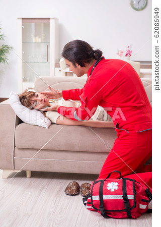 Young male paramedic visiting young woman 62086949