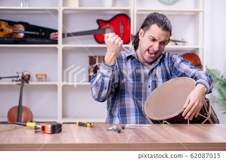 Young handsome repairman repairing drum 62087015