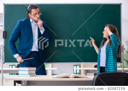 Young handsome teacher and female student in the classroom Young handsome teacher and female student in the classroom 62087159