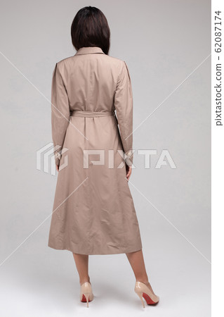 Beautiful woman in trench coat posing in studio 62087174