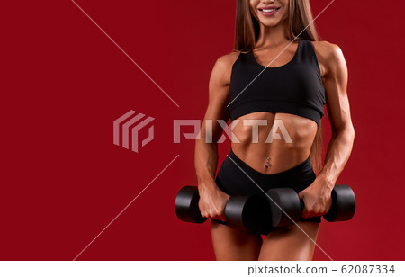 Crop of smiling fitnesswoman holding dumbbells. Crop of smiling fitnesswoman holding dumbbells. 62087334