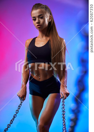 Fit girl posing holding chains. Fit girl posing holding chains. 62087350