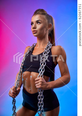 Muscular woman holding chains on neck. Muscular woman holding chains on neck. 62087351