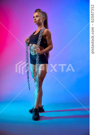 Muscular woman holding chains on neck. 62087352
