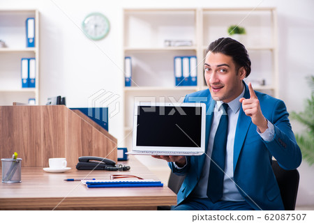 Young handsome businessman sitting in the office Young handsome businessman sitting in the office 62087507