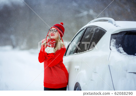 A woman against a snowy valley dressed in mittens and a red swea A woman against a snowy valley dressed in mittens and a red swea 62088290