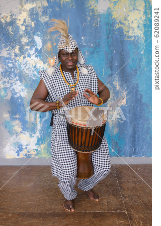 African artist in traditional clothes playing djembe drum 62089241