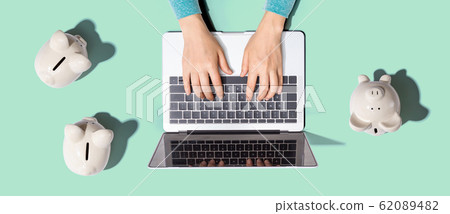 Person using laptop with three piggy banks Person using laptop with three piggy banks 62089482