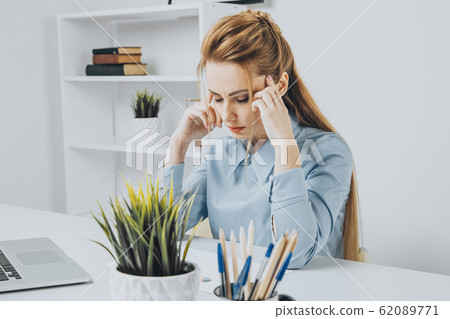 Young office girl sitting at her workplace feeling bad. Woman has a headache. Young office girl sitting at her workplace feeling bad. Woman has a headache. 62089771