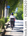 Rear view of a woman riding a bicycle with a child seat attached 62090620