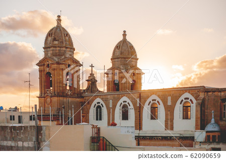 Sunset behind bell towers of Our Lady of Mount Carmel parish church. Gzira, Malta 62090659